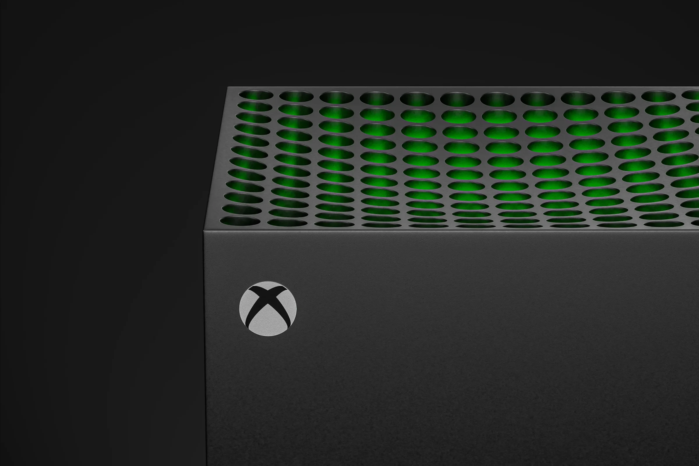 Black Xbox console with green light glowing through its top ventilation